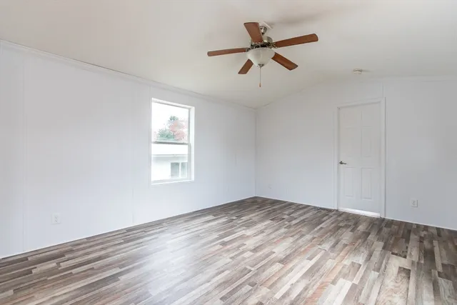 a view of empty room with wooden floor and ceiling fan