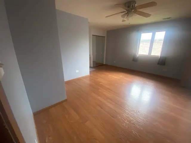 an empty room with a window and ceiling fan