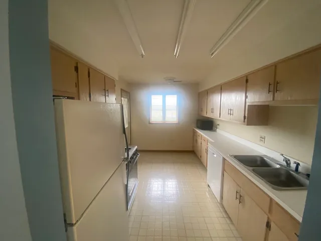 a kitchen with a sink a refrigerator and cabinets