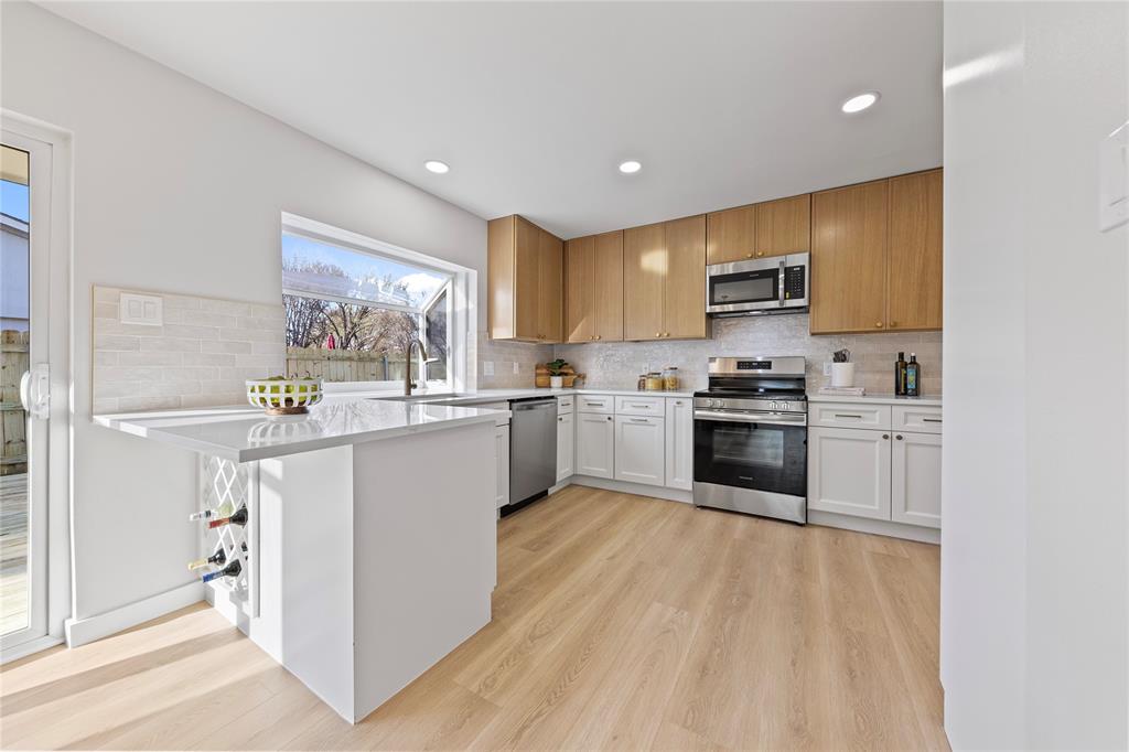3121 Wayfarer Road Bedford, TX 76021 - Photo 16 of 32 Kitchen featuring a peninsula, stainless steel appliances, light wood-style floors, backsplash, and recessed lighting