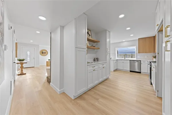 a view of a kitchen with kitchen island a sink wooden floor and stainless steel appliances