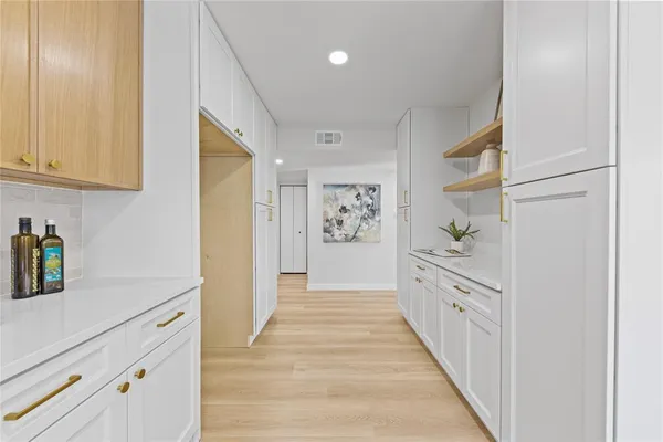 a hallway with white cabinets and wooden floor