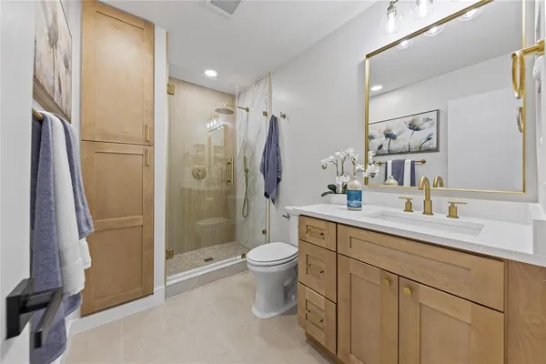 a bathroom with a double vanity sink toilet mirror and shower