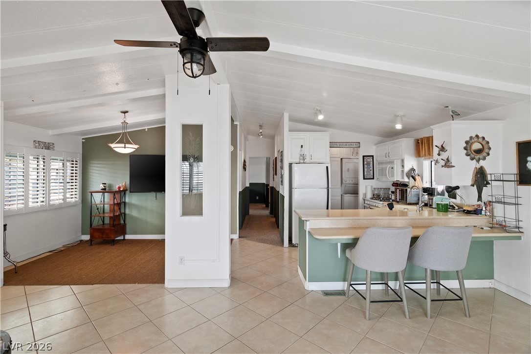 1655 Granada Street Laughlin, NV 89029 - Photo 11 of 76 Kitchen with a breakfast bar, a peninsula, light countertops, white cabinets, and white appliances
