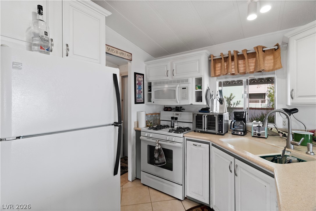 1655 Granada Street Laughlin, NV 89029 - Photo 14 of 76 Kitchen featuring white appliances, light countertops, white cabinets, and light tile patterned flooring