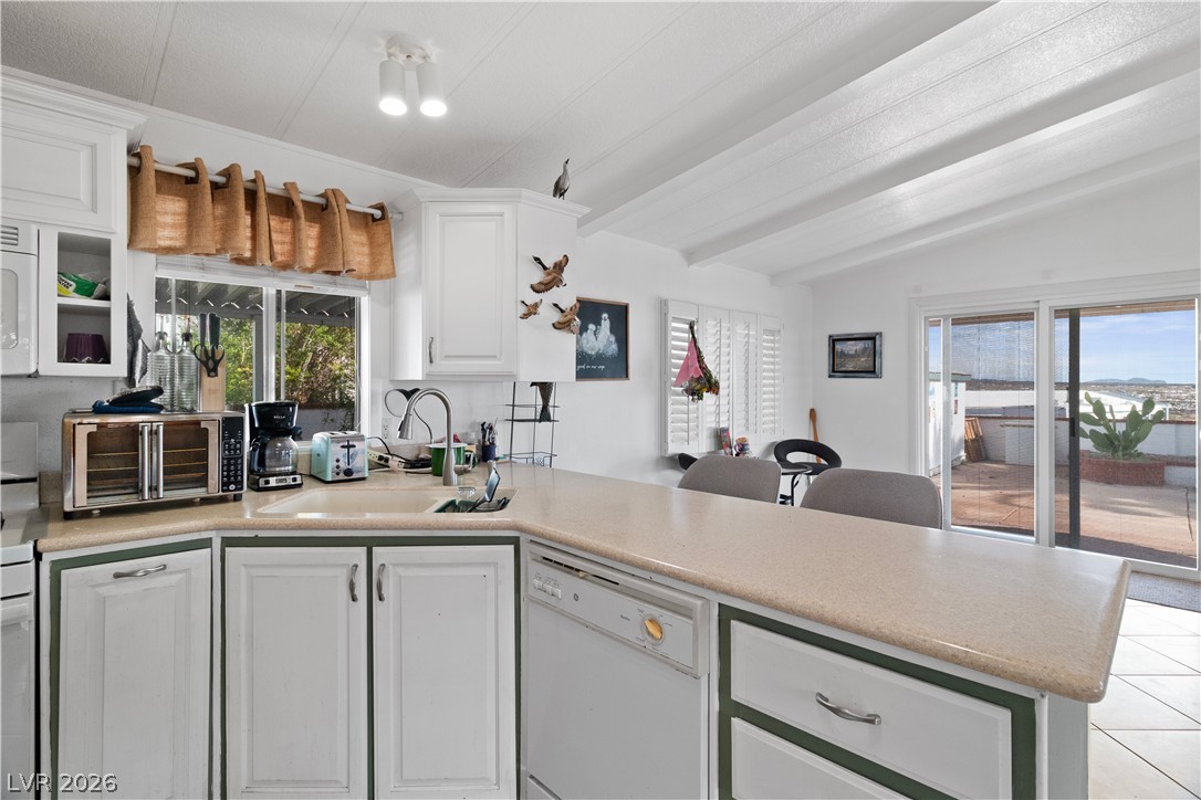1655 Granada Street Laughlin, NV 89029 - Photo 17 of 76 Kitchen with white cabinets, light countertops, white appliances, a peninsula, and beam ceiling