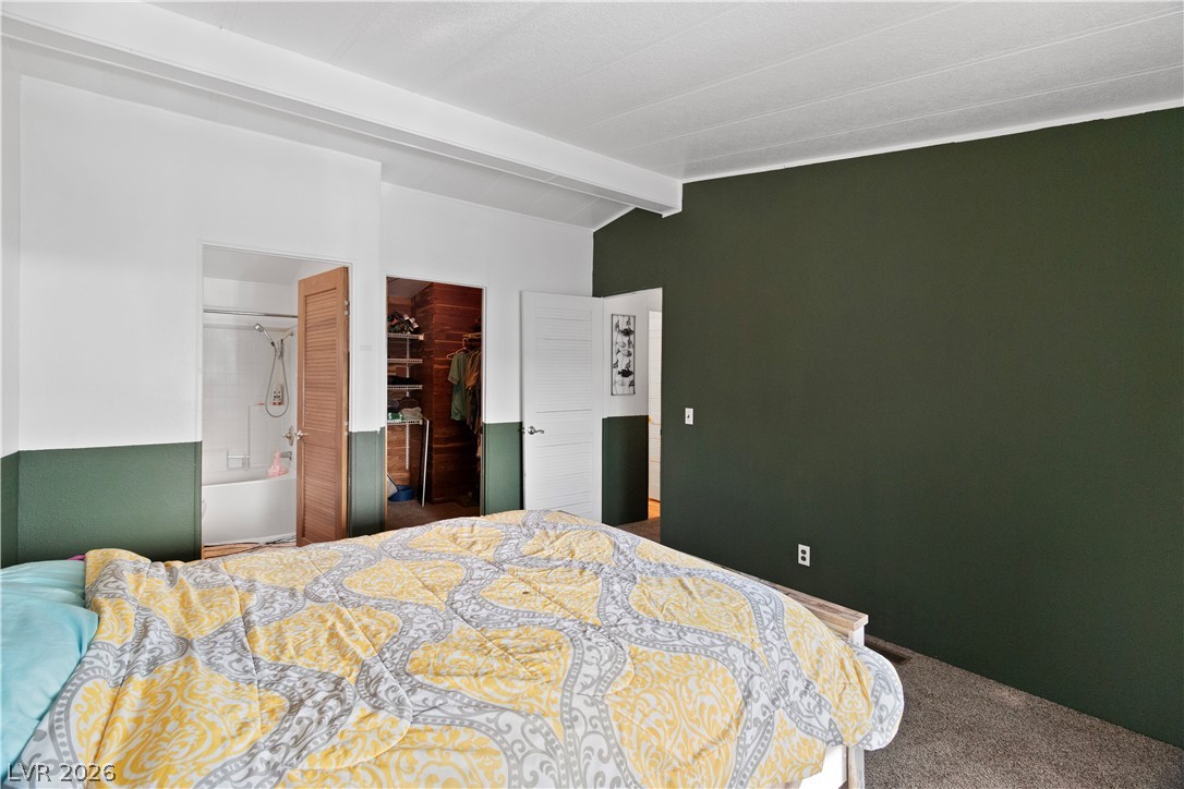 1655 Granada Street Laughlin, NV 89029 - Photo 27 of 76 Primary Bedroom with dark colored carpet, vaulted ceiling with beams, and a walk in closet