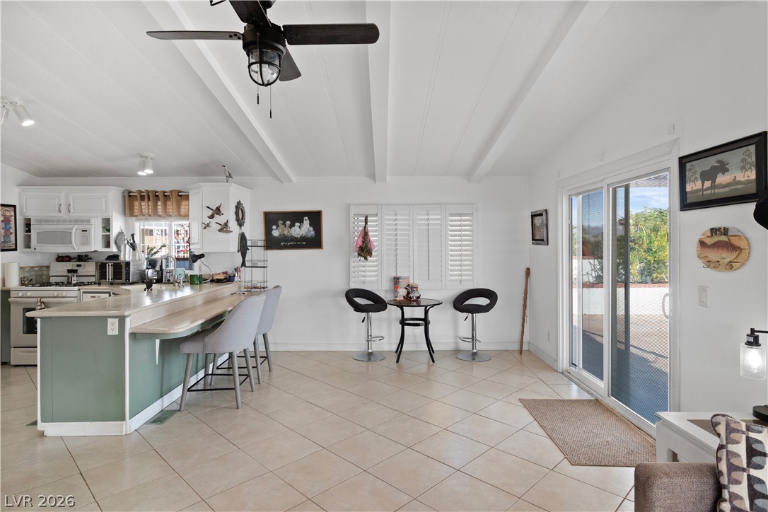 1655 Granada Street Laughlin, NV 89029 - Photo 10 of 76 Kitchen featuring a breakfast bar, gas range oven, light countertops, white microwave, and ceiling fan