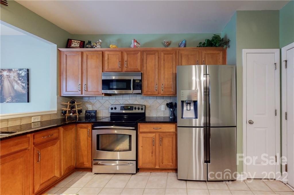 9136 Redmond Trace Road Charlotte, NC 28277 - Photo 15 of 37 a kitchen with granite countertop a refrigerator stove and microwave