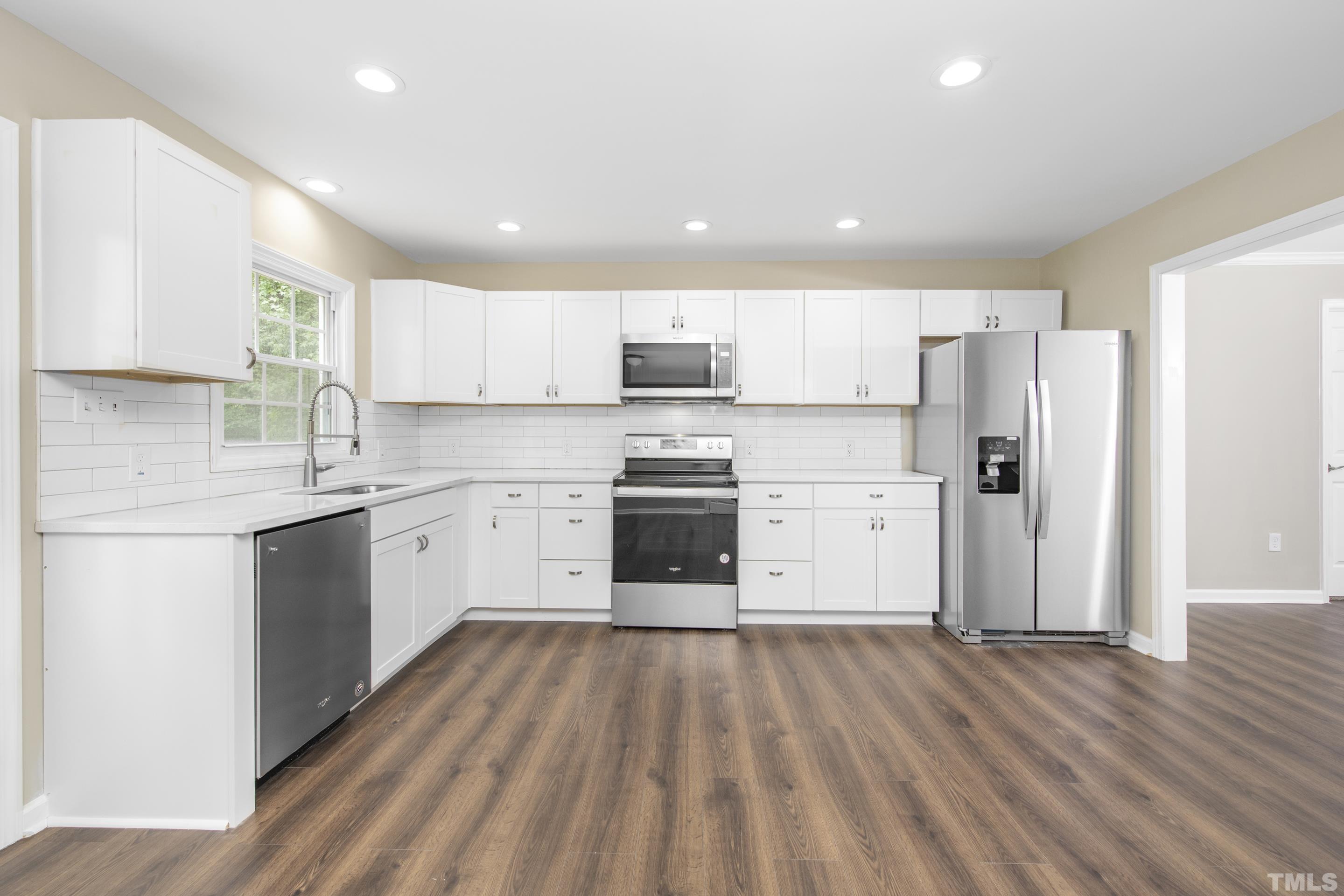 212 Junction Road Durham, NC 27703 - Photo 8 of 50 a kitchen with wooden floors stainless steel appliances and white cabinets