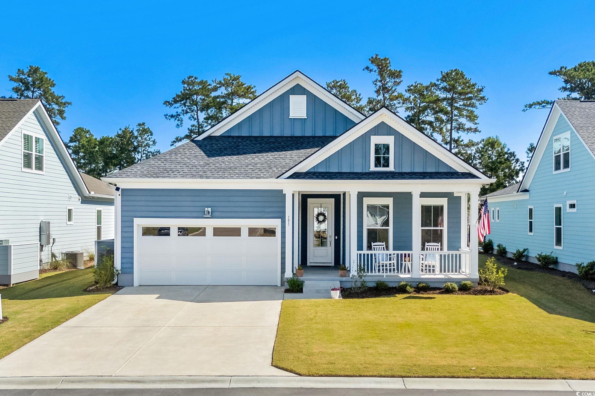 View of front of house with board and batten siding, a porch, a front yard, and driveway