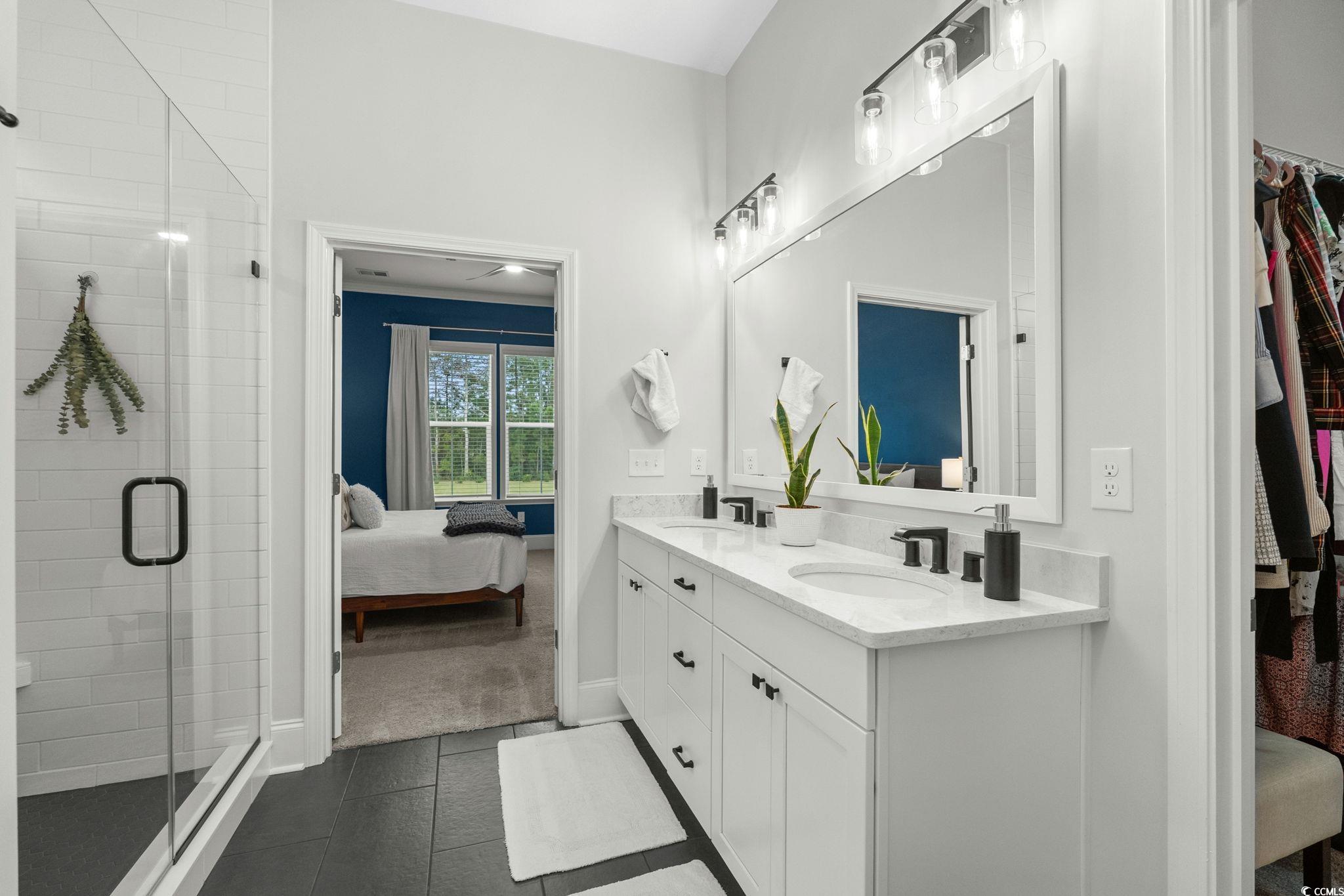 191 Blackwater Drive Murrells Inlet, SC 29576 - Photo 19 of 40 Bathroom featuring connected bathroom, a stall shower, double vanity, a walk in closet, and dark tile patterned flooring