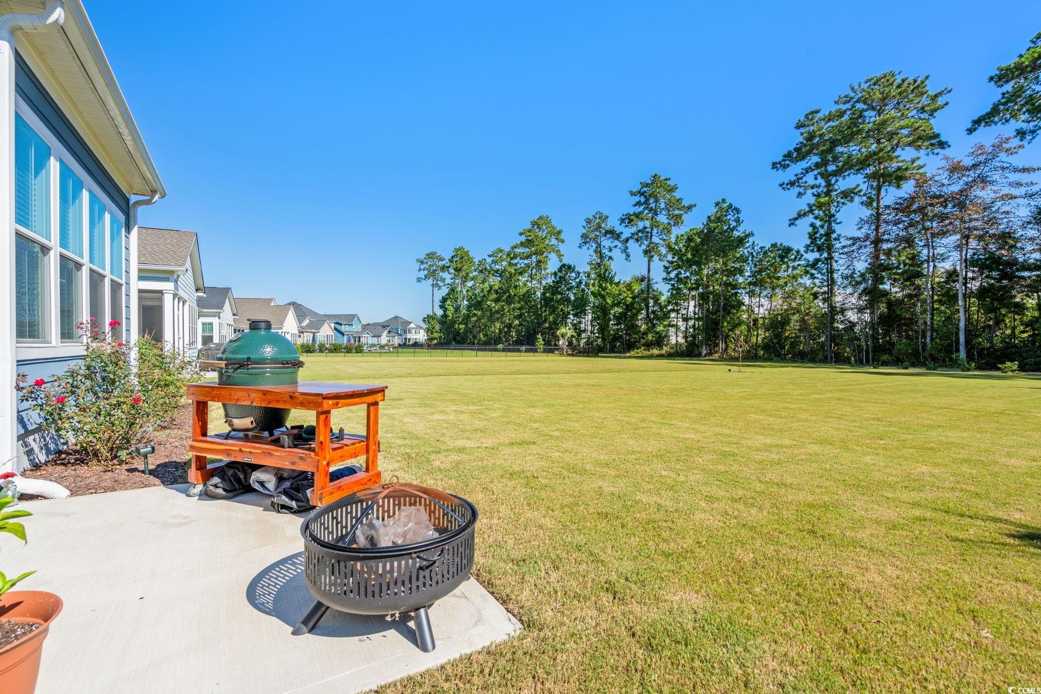 191 Blackwater Drive Murrells Inlet, SC 29576 - Photo 31 of 40 View of grassy yard featuring a patio area, a fire pit, and a residential view