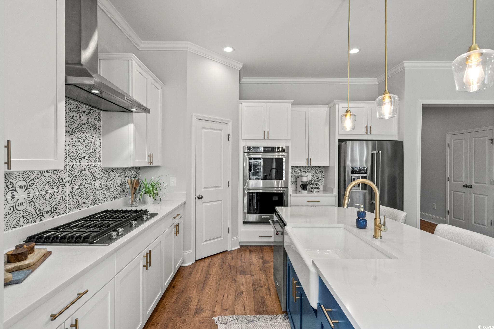 191 Blackwater Drive Murrells Inlet, SC 29576 - Photo 9 of 40 Kitchen featuring white cabinetry, wall chimney exhaust hood, pendant lighting, appliances with stainless steel finishes, and crown molding
