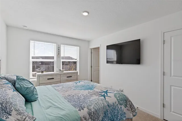 a spacious bedroom with a bed and a flat screen tv