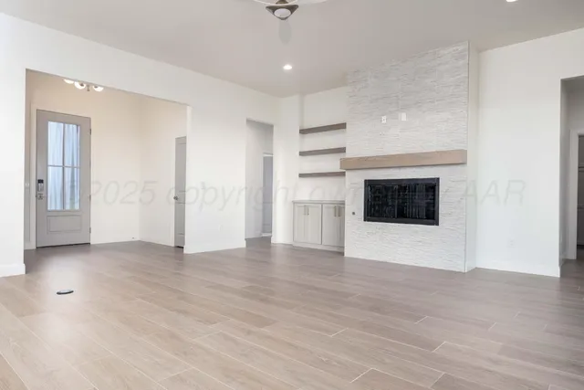a view of an empty room with cabinet and a fireplace