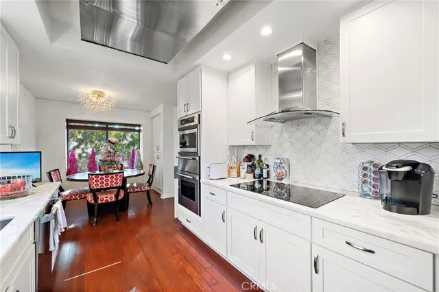 a kitchen with stainless steel appliances granite countertop a refrigerator a sink dishwasher a dining table and chairs with wooden floor