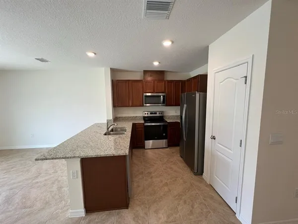 a kitchen with granite countertop a refrigerator and a stove top oven