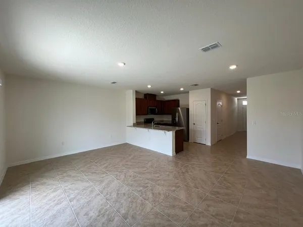 an empty room with kitchen view and a window