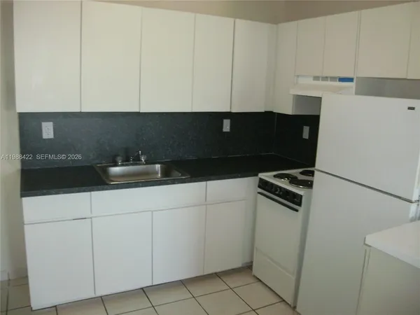 a kitchen with white cabinets and appliances