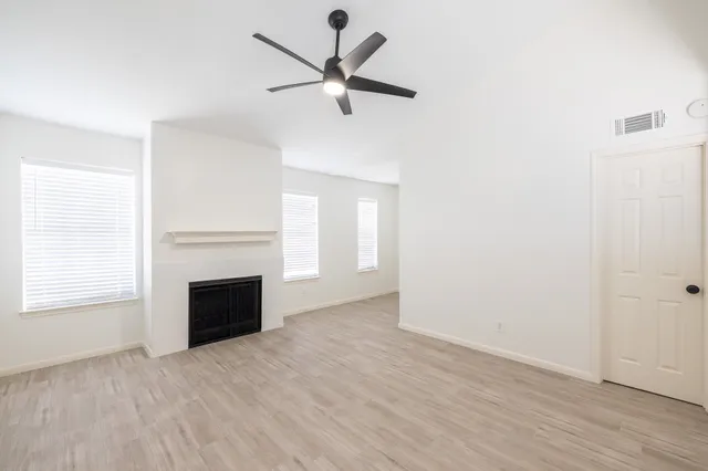 an empty room with ceiling fan and window