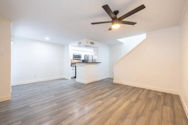 an empty room with wooden floor and ceiling fan