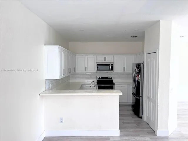 a kitchen with stainless steel appliances a sink a stove a refrigerator a microwave and cabinets