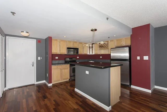 a kitchen with stainless steel appliances kitchen island granite countertop a refrigerator and a microwave
