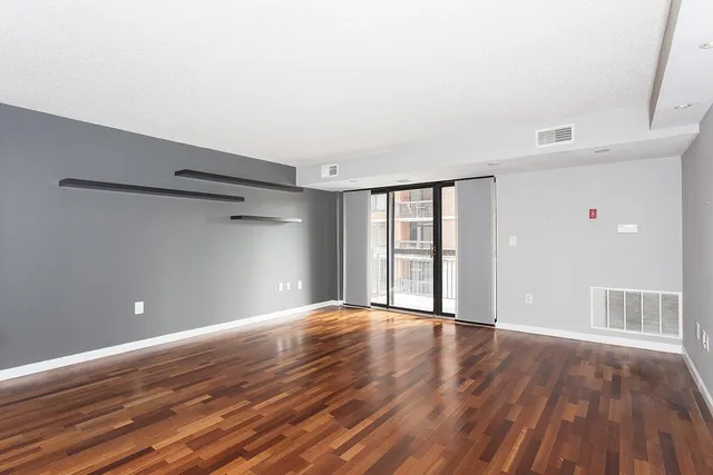a view of an empty room with wooden floor and a window