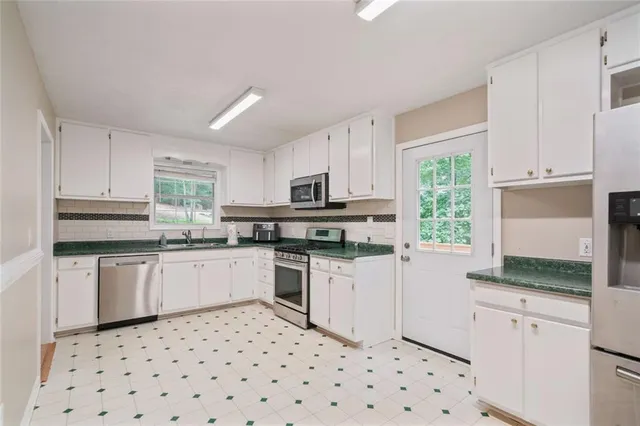 a kitchen with granite countertop appliances a sink a stove a microwave and cabinets