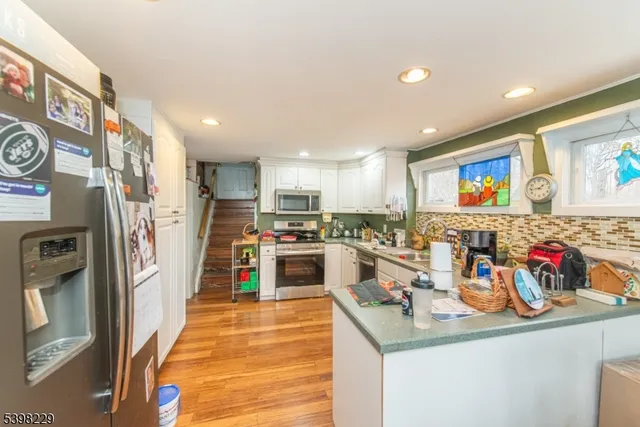 a kitchen with stainless steel appliances wooden floor and large refrigerator