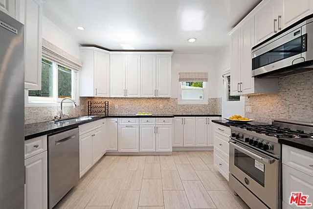 a kitchen with granite countertop wooden cabinets stainless steel appliances and a window