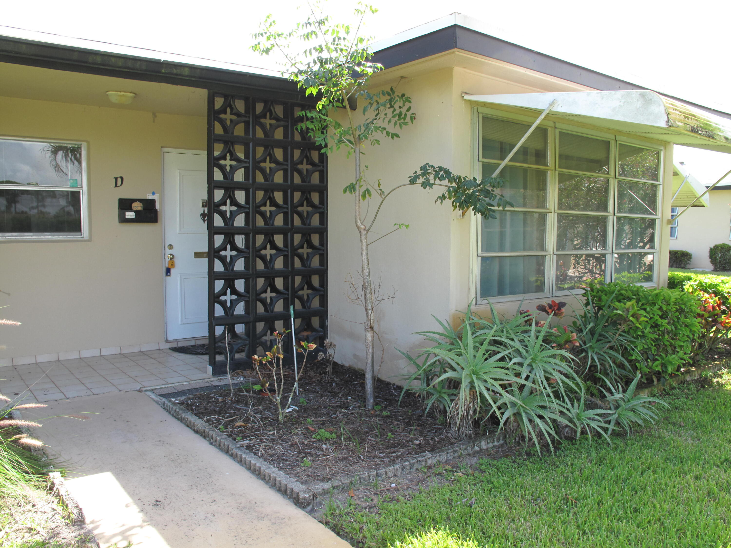 892 North High Point Boulevard North, Unit D Delray Beach, FL 33445 - Photo 2 of 44 a front view of a house with a yard