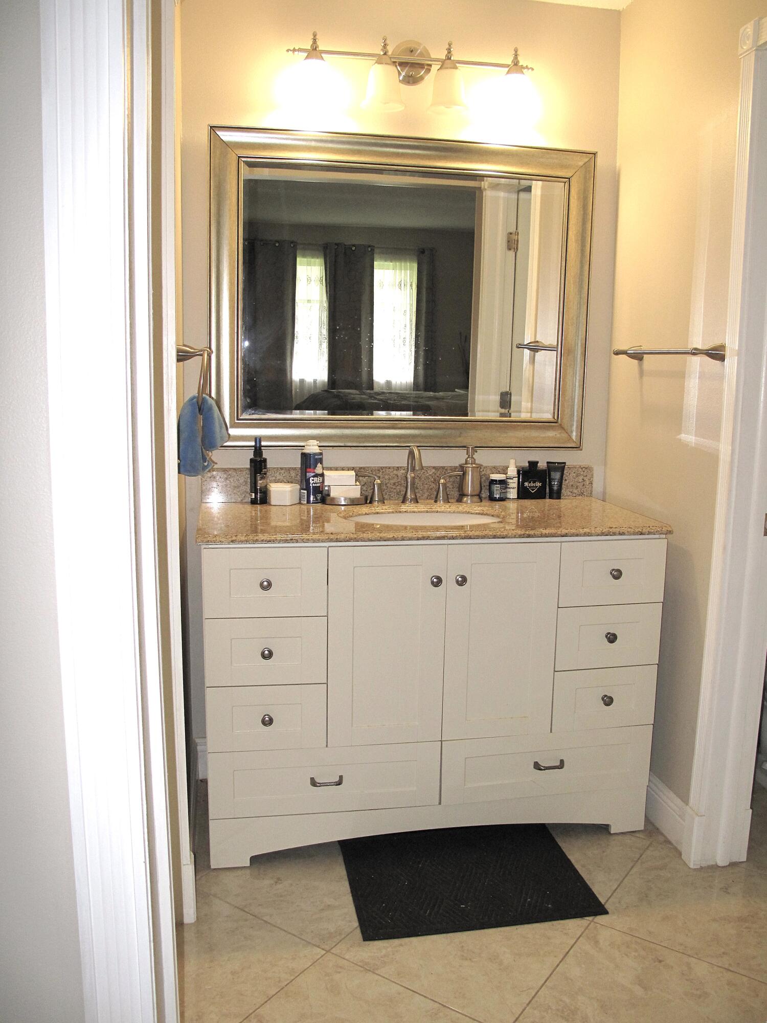 892 North High Point Boulevard North, Unit D Delray Beach, FL 33445 - Photo 25 of 44 a bathroom with a double vanity sink and mirror
