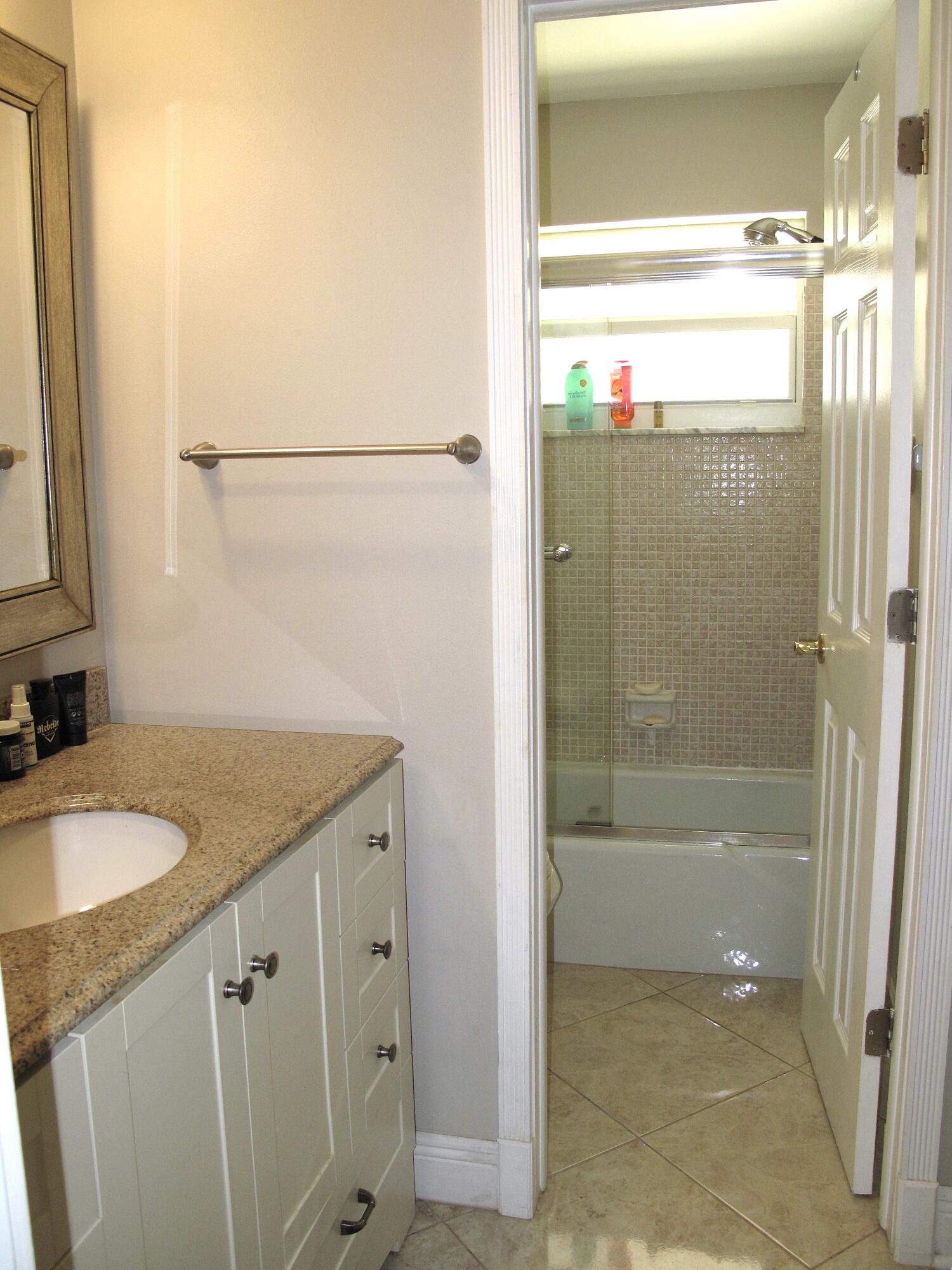 892 North High Point Boulevard North, Unit D Delray Beach, FL 33445 - Photo 27 of 44 a bathroom with a granite countertop sink a mirror and shower
