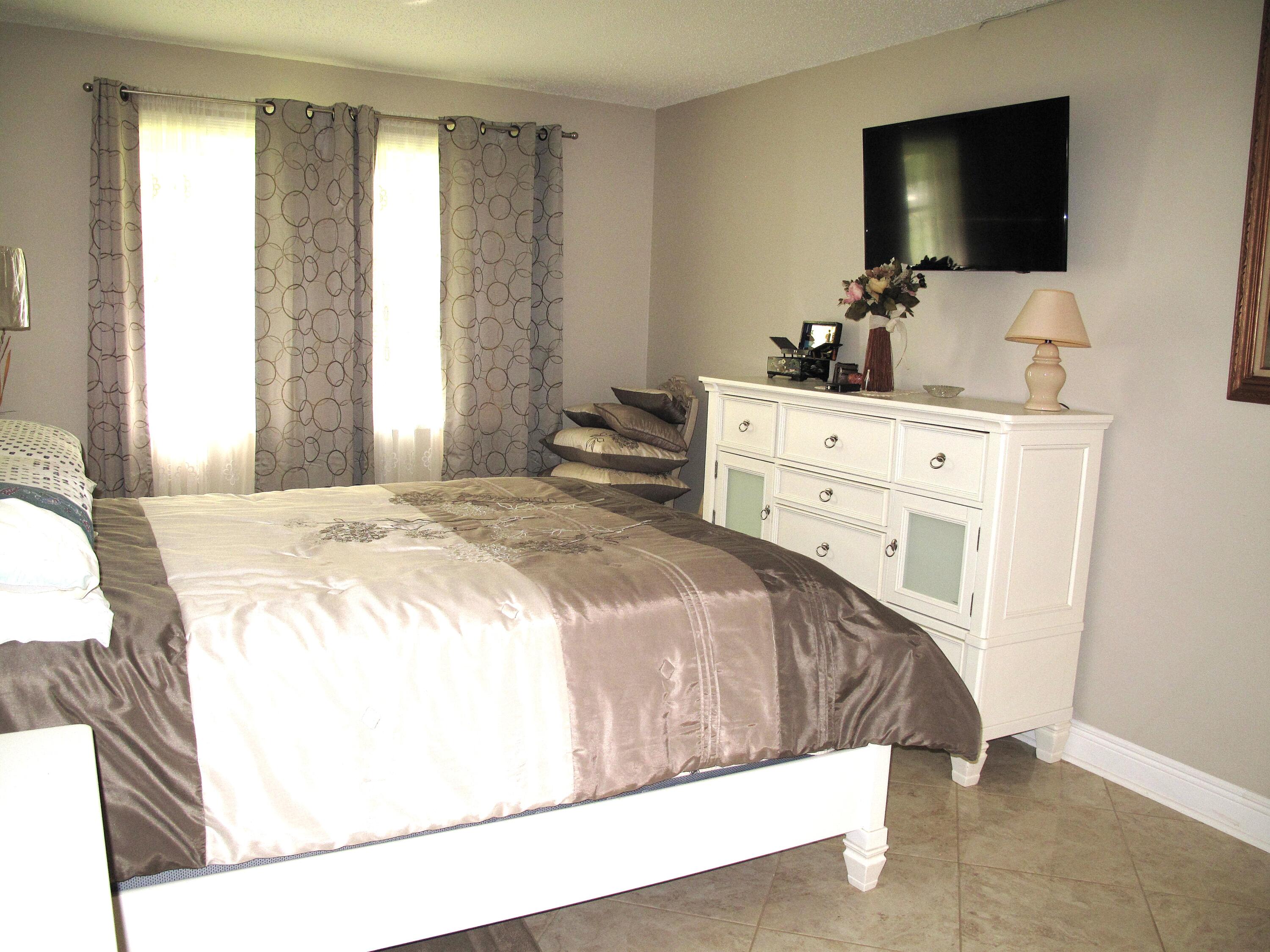 892 North High Point Boulevard North, Unit D Delray Beach, FL 33445 - Photo 30 of 44 a bedroom with a bed and a flat screen tv