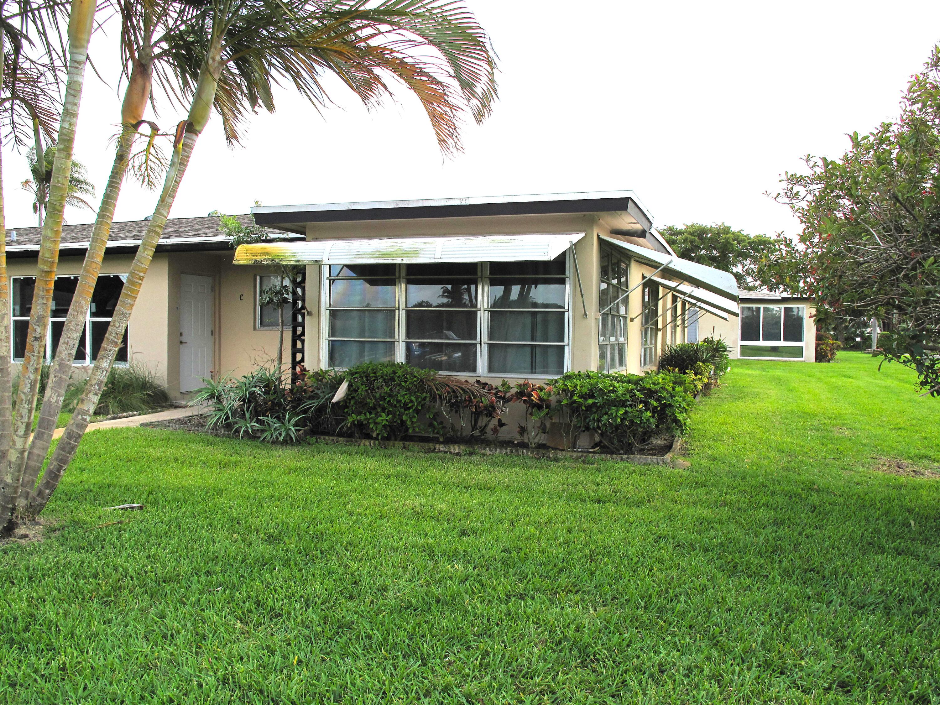 892 North High Point Boulevard North, Unit D Delray Beach, FL 33445 - Photo 3 of 44 a front view of a house with a yard and trees