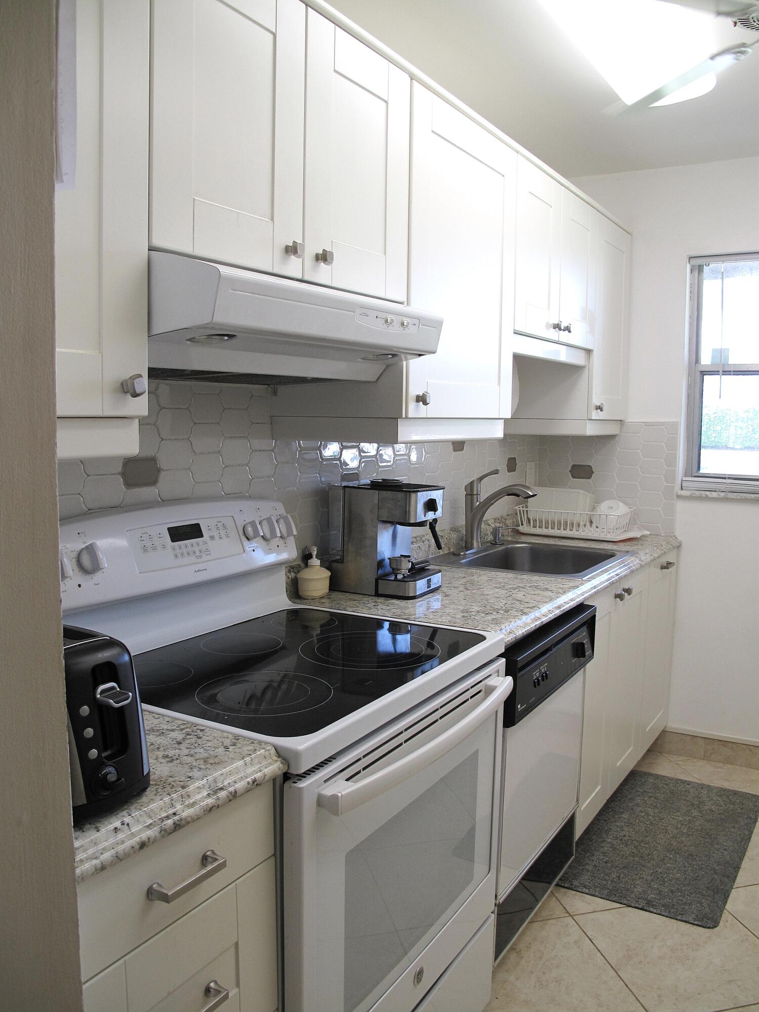 892 North High Point Boulevard North, Unit D Delray Beach, FL 33445 - Photo 7 of 44 a kitchen with granite countertop a sink stainless steel appliances and cabinets