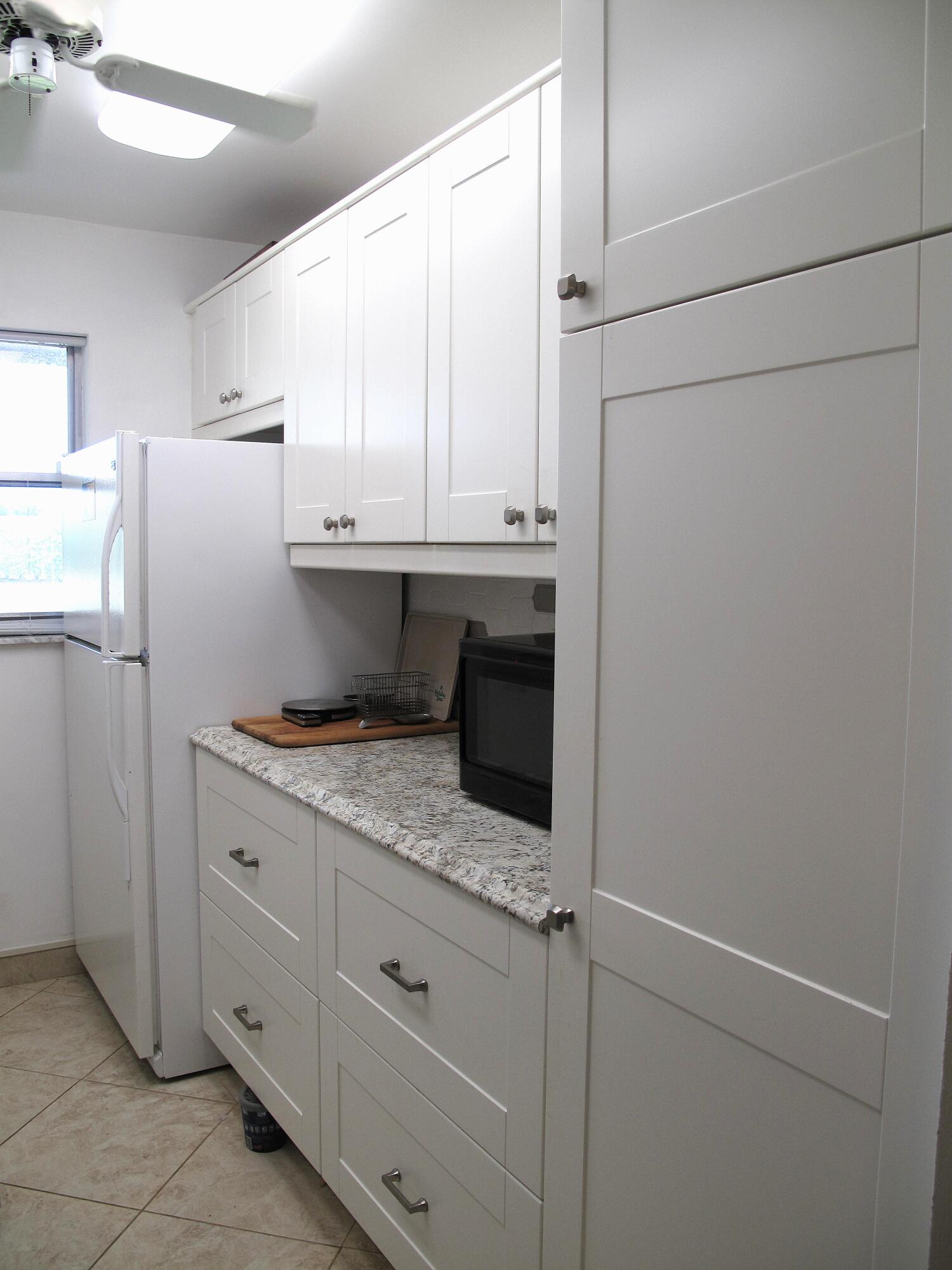 892 North High Point Boulevard North, Unit D Delray Beach, FL 33445 - Photo 8 of 44 a kitchen with stainless steel appliances granite countertop a refrigerator sink and white cabinets