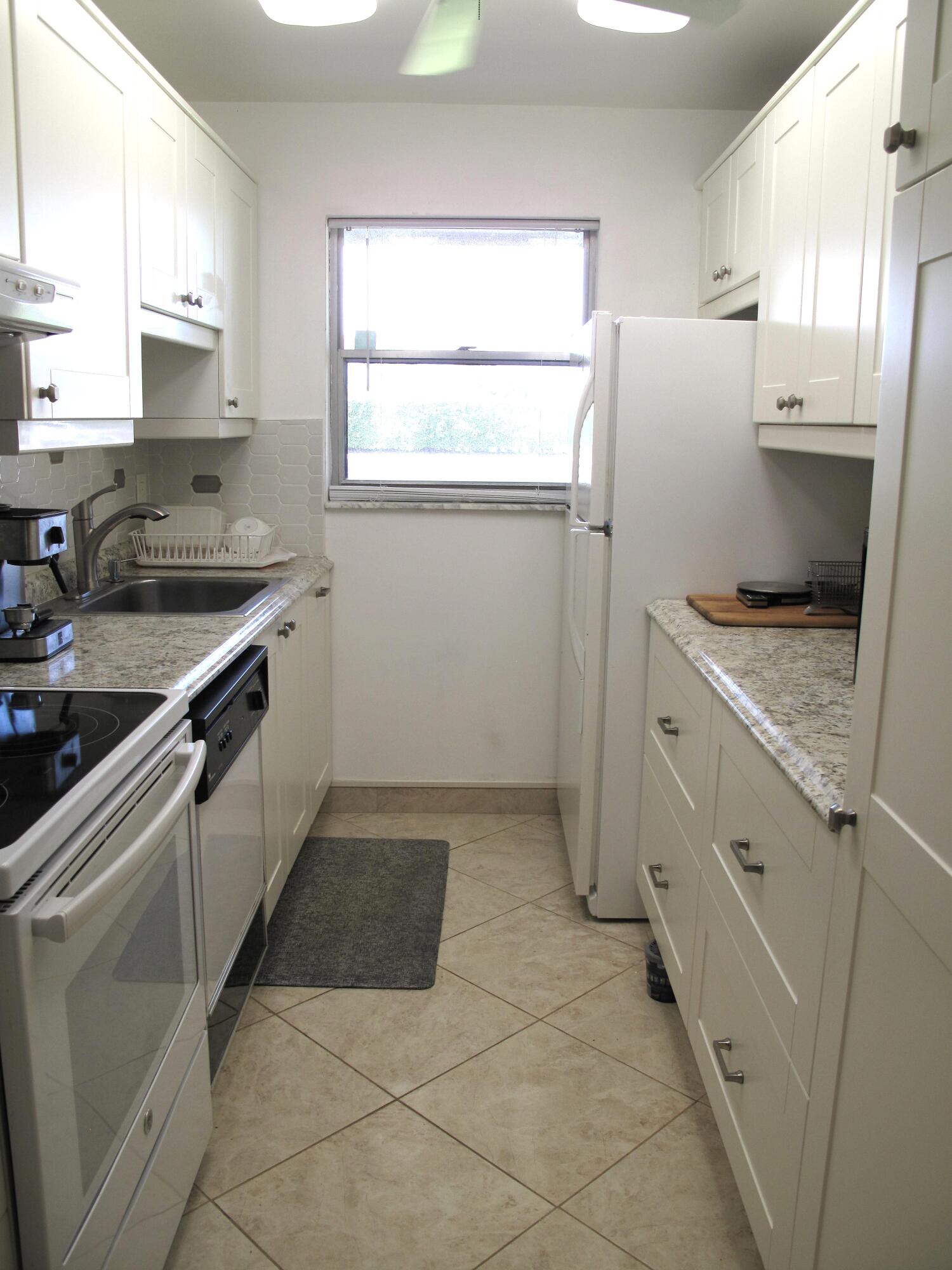 892 North High Point Boulevard North, Unit D Delray Beach, FL 33445 - Photo 9 of 44 a kitchen with a sink stove and refrigerator