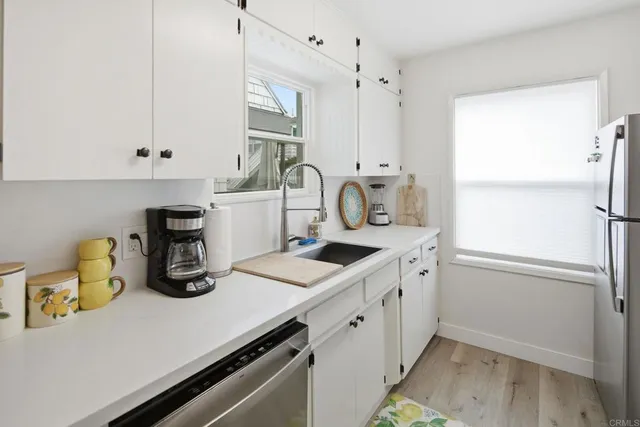 a kitchen with stainless steel appliances granite countertop a stove a sink dishwasher and a refrigerator with wooden floor