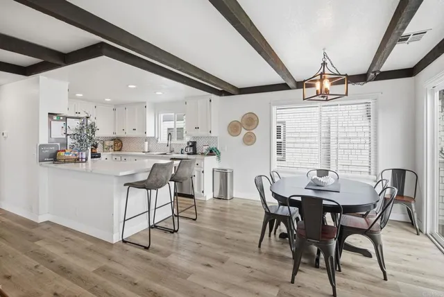 a living room with furniture kitchen view and a wooden floor