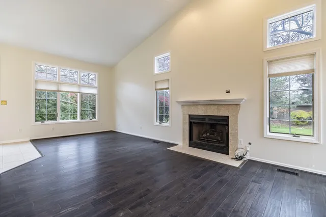 an empty room with wooden floor fireplace and windows