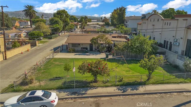 an aerial view of a tennis ground and a cars park side of the road