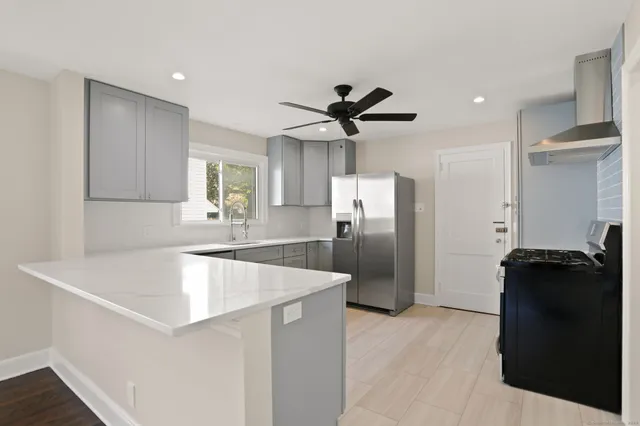 a kitchen with stainless steel appliances granite countertop a refrigerator a sink a stove and a refrigerator