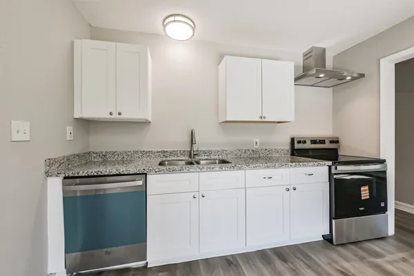 a kitchen with granite countertop white cabinets and a stove