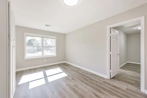 an empty room with wooden floor and windows