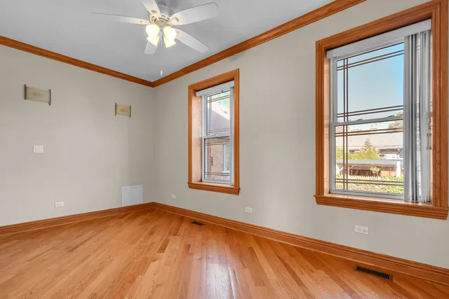 a view of empty room with wooden floor and fan