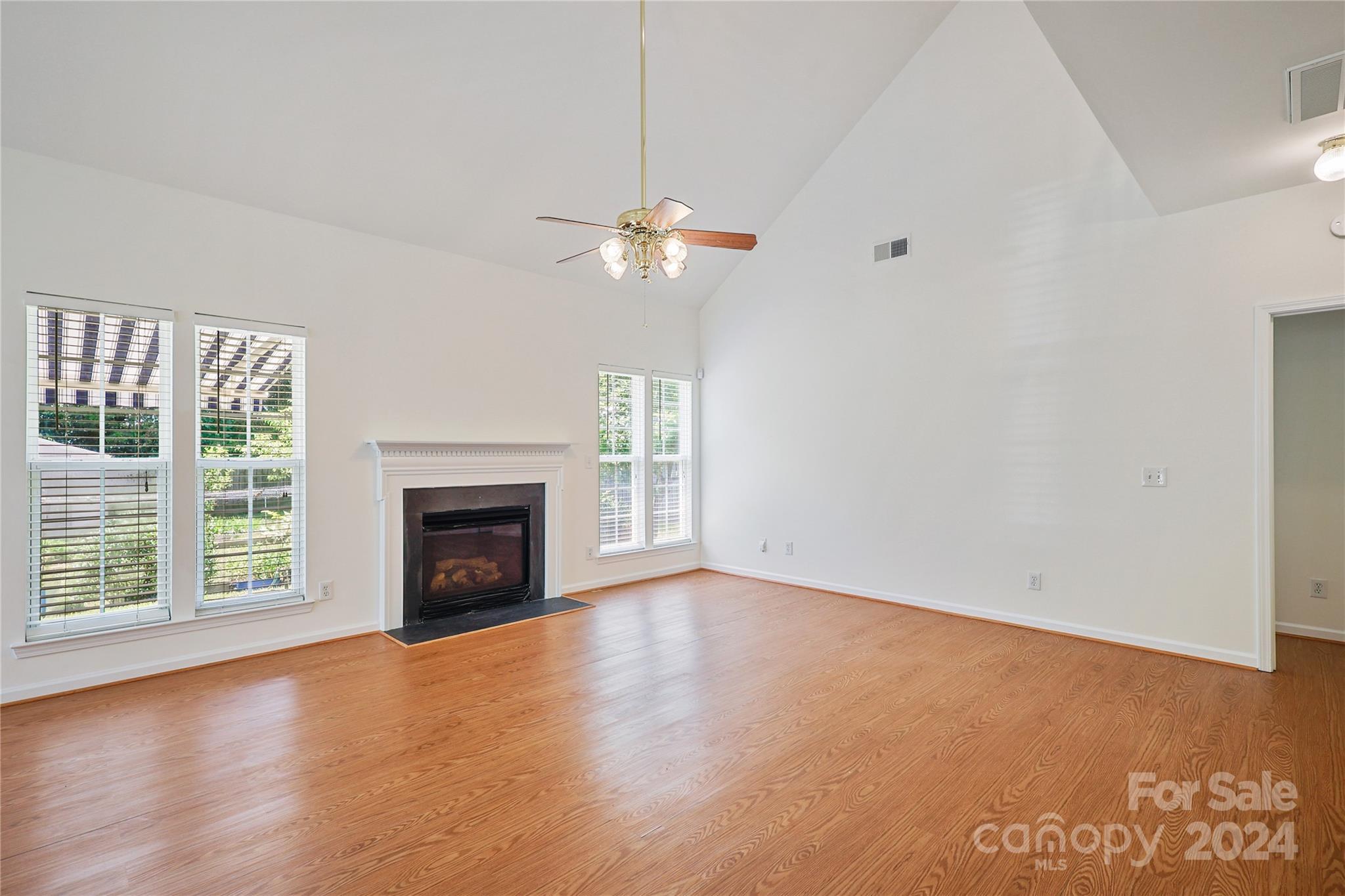 14336 Williams Glenn Road Charlotte, NC 28273 - Photo 9 of 39 an empty room with windows fireplace and a chandelier fan
