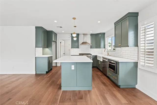 a large kitchen with stainless steel appliances granite countertop a large stove a sink dishwasher and a refrigerator with wooden floor